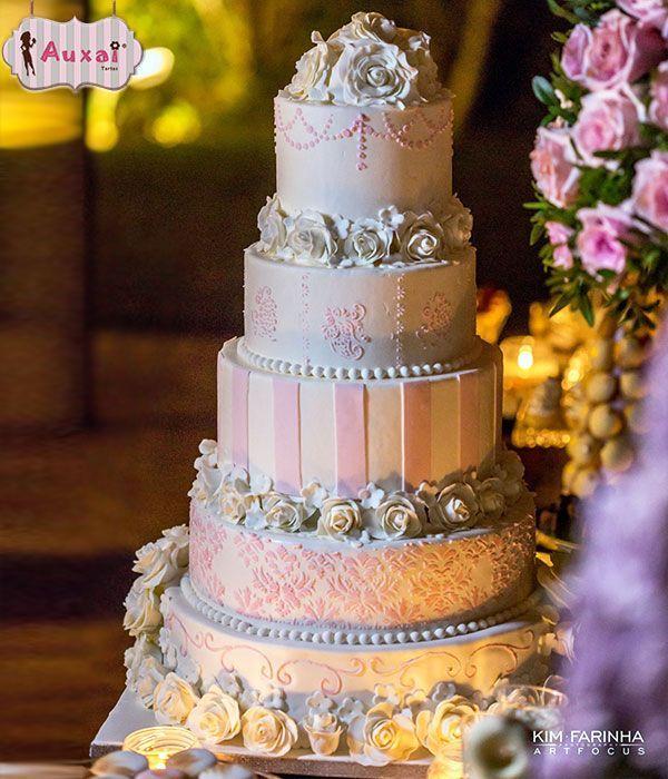 Tarta de boda de cinco pisos decorada con flores blancas y detalles en tonos rosa