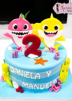 Tarta Baby Shark con tiburón rosa y tiburón amarillo, número 2 y nombres Daniela y Manuela en Auxai Tartas