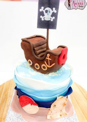 Tarta barco pirata con barco de madera, bandera negra con calavera, ancla y elementos del tesoro en Auxai Tartas