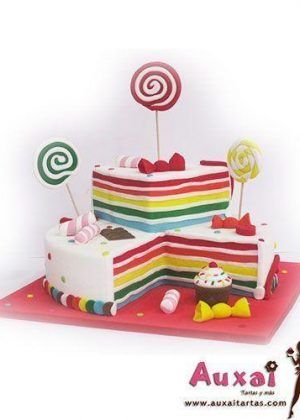 Tarta arcoiris y chuches con capas multicolores y decoración de piruletas, caramelos y golosinas de fondant