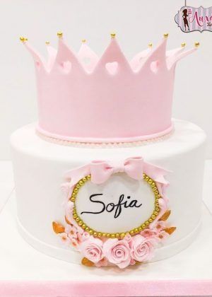 Tarta corona de princesa en blanco con gran corona rosa y dorada, marco con nombre Sofia y rosas rosas
