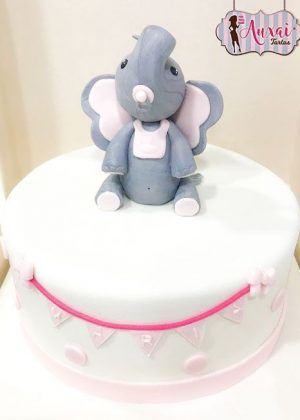 Tarta animales elefante gris y rosa con elefante gris sentado, babero blanco y guirnalda de banderines rosas