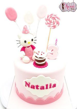 Tarta Hello Kitty cumpleaños en rosa con figura de Hello Kitty con gorrito de fiesta, globos, pirulí, número 3 y placa con nombre NATALIA