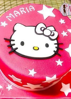 Tarta cara Hello Kitty 2D en rosa brillante con cara grande de Hello Kitty, estrellas blancas y nombre MARIA en la superficie