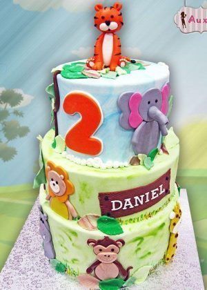 Tarta animales 2 años de dos pisos con tigre en la parte superior, elefante, león, mono, jirafa y nombre DANIEL en placa de madera