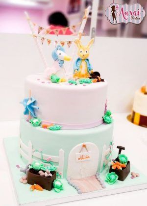 Tarta granja animales infantil de dos pisos con conejito amarillo y patito blanco en la parte superior, valla, huerto y nombre ALICIA en la puerta