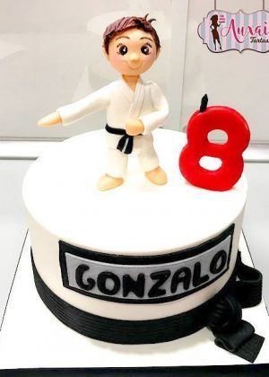 Tarta karateca personalizada en blanco con figura de karateca en pose, número 8 rojo y nombre GONZALO en placa de cinturón negro