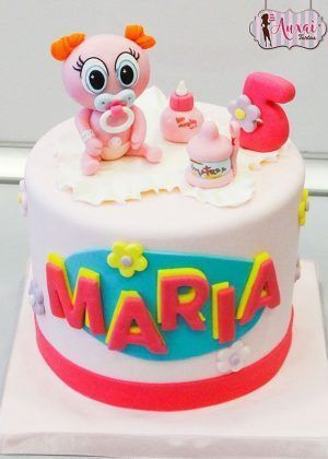 Tarta Ksi meritos con complementos en blanco y rosa con muñequita Ksi Meritos, biberón, número 5 y nombre MARIA en letras grandes