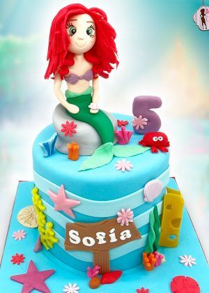 Tarta Disney Princesa La Sirenita con figura de Ariel sentada sobre roca, número 5 y nombre SOFÍA en cartel de madera