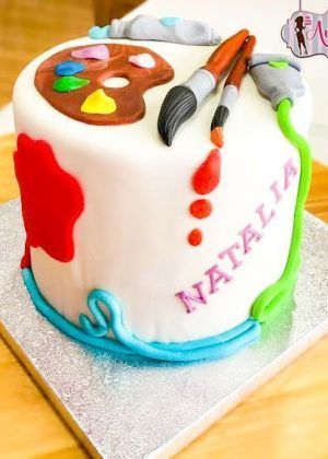 Tarta pintura colorida con paleta de artista, pinceles y efectos de pintura en colores vivos sobre superficie blanca