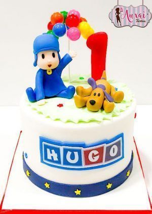 Tarta Pocoyo 1 año con figuras 3D de Pocoyo y Lou, arco de globos y número 1 rojo sobre superficie blanca