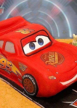 Tarta Disney Rayo McQueen en 3D figura completa del coche rojo con ojos expresivos y número 95 sobre base de pista