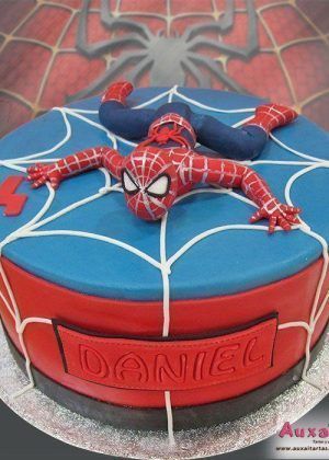 Tarta super héroes Spiderman tumbado con figura 3D de Spiderman sobre tela de araña azul y roja, nombre Daniel en placa lateral
