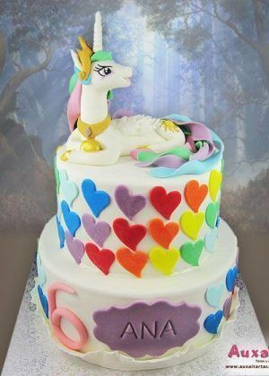 Tarta unicornio My Little Pony de dos pisos con figura 3D de unicornio blanco con cuerno dorado y melena multicolor, corazones de colores y nombre ANA en placa morada con número 6
