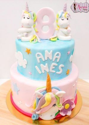 Tarta unicornio 2 pisos con dos unicornios blancos sentados, número 8 rosa, nombre ANA INES en letras blancas y cabeza de unicornio con melena multicolor en el piso inferior
