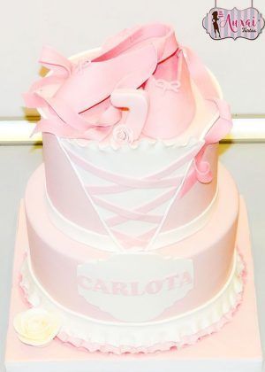 Tarta zapatillas bailarina fondant de dos pisos con zapatillas de ballet rosa y cintas, número 7, lazos cruzados y nombre CARLOTA en placa blanca con volante romántico