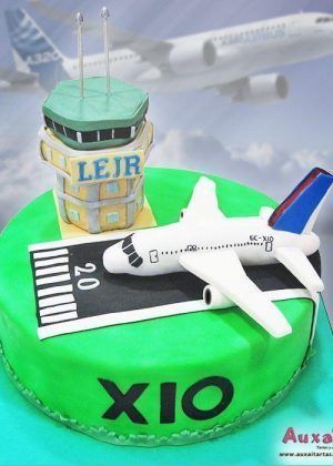 Tarta Avión y Torre de Control personalizada con base verde lima, avión blanco con detalles en azul y torre de control modelada en tonos amarillo dorado, creada por Auxai Tartas en Madrid