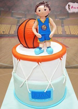 Tarta baloncesto personalizada con figura de jugador en mate, aro naranja y blanco, colores azul y blanco, diseño artesanal professional