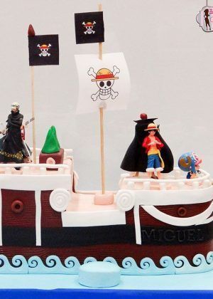 Tarta barco One Piece personalizada con Thousand Sunny, personajes del anime, bandera pirata Jolly Roger, base azul agua y acabados profesionales