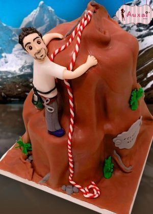 Tarta escalador temática con fondant chocolate, detalles en verde bosque, figuras de escalador, cuerdas comestibles y elementos de montaña para celebraciones de aventura