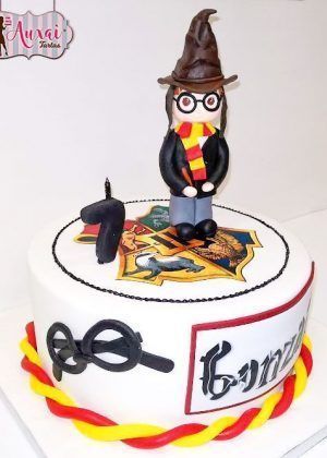 Tarta con muñeco Harry Potter diseñada con fondant rojo brillante premium y muñeco de mago modelado en fondant con detalles cinematográficos