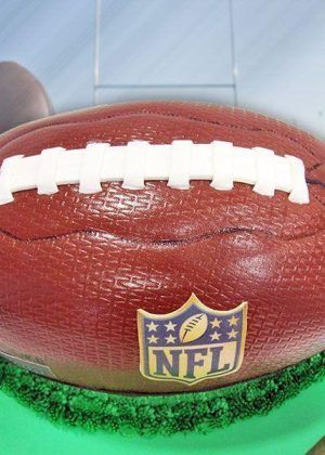 Tarta balón fútbol americano con costuras blancas y escudo NFL en Auxaitartas