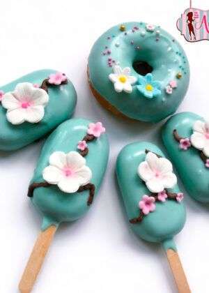 Cake bars flor de cerezo con cobertura turquesa, flores blancas y rosadas de cerezo y un donut a juego