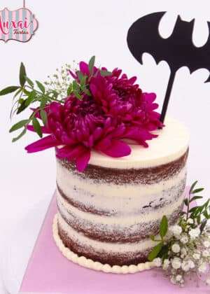 Tarta boda Batman naked cake con flores fucsia, hojas verdes y topper negro del logo de Batman