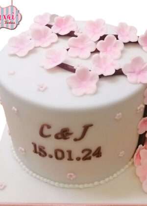 Tarta boda flor de cerezo con flores rosadas de sakura, rama marrón y personalización C & J 15.01.24 en fondo blanco