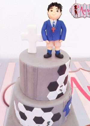 Tarta comunión fútbol gris con figura 3D de niño y cruz en Auxaitartas