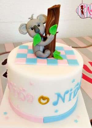 Tarta gender reveal koala con figura de koala gris abrazando un tronco y texto Niño Niña en colores pastel