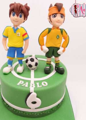 Tarta futbol inazuma eleven madrid con personajes modelados en fondant sobre campo de fútbol verde para cumpleaños infantil