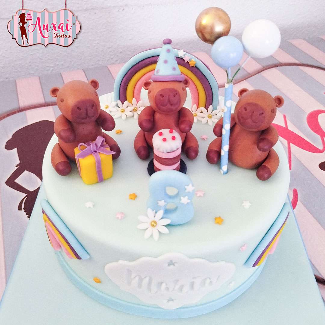 Tarta de cumpleaños personalizada madrid con figuras de fondant de capibaras, arcoíris y globos en tonos pastel