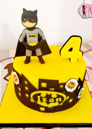 Tarta infantil personalizada de Batman con cobertura de fondant amarillo, silueta de Gotham y figura modelada en 3D en Madrid.
