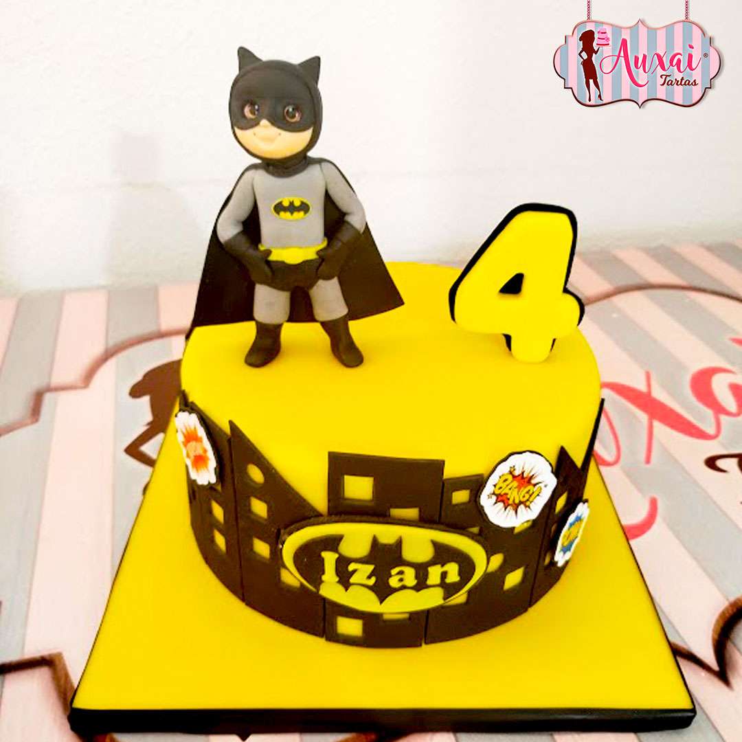 Tarta infantil personalizada de Batman con cobertura de fondant amarillo, silueta de Gotham y figura modelada en 3D en Madrid.