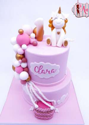 Tarta infantil unicornio y globos de dos pisos en color lila y rosa pastel con cascada de fondant y unicornio modelado en Madrid.