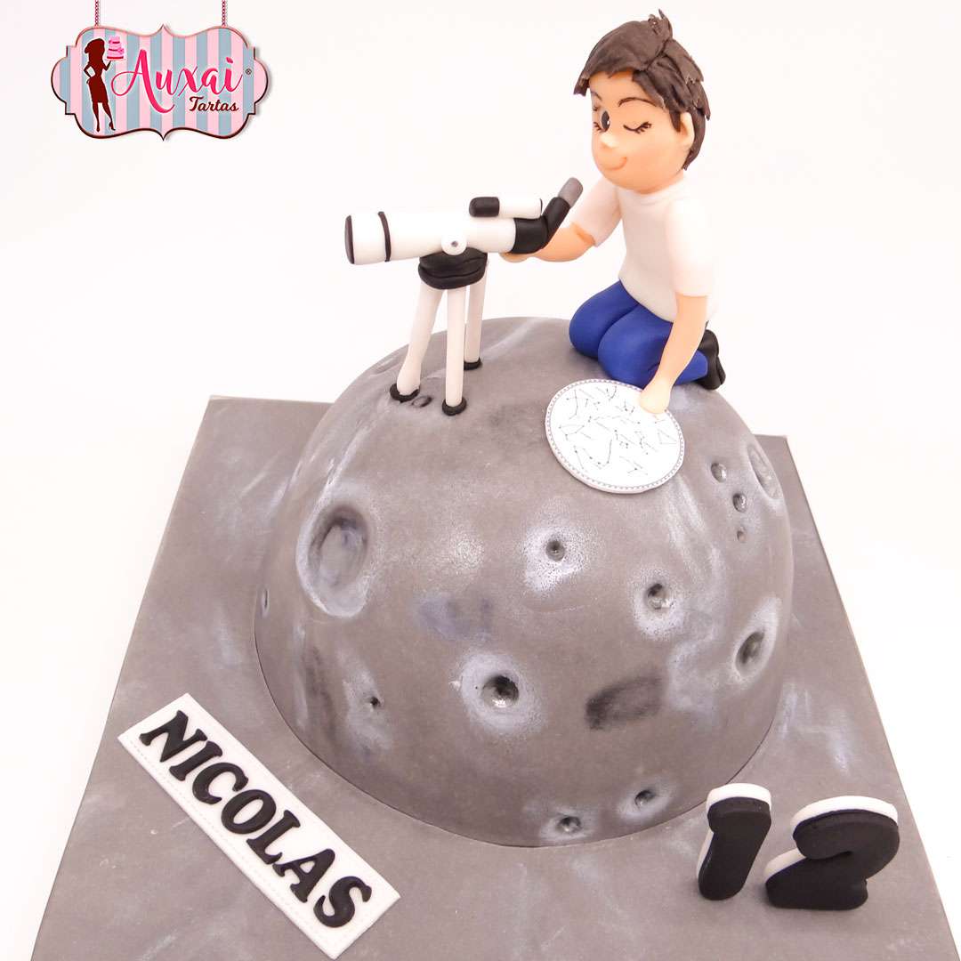 Tarta nino astronomo modelada en fondant con forma de luna gris con cráteres y telescopio en Madrid.
