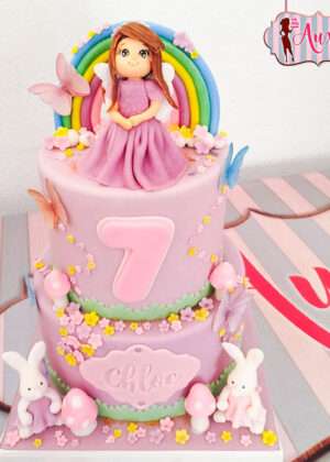 Tarta princesa arcoiris madrid de dos pisos en tonos pastel con figura de princesa modelada a mano y conejitos de azúcar para cumpleaños infantil de diseño por Auxai Tartas