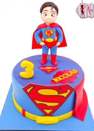 Tarta infantil de superman personalizada madrid con figura modelada en 3D del personaje y capa roja sobre fondo azul.